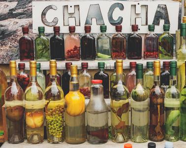 格鲁吉亚酒精饮料 chacha 在不同的水果和草药的瓶子销售在市场上照片